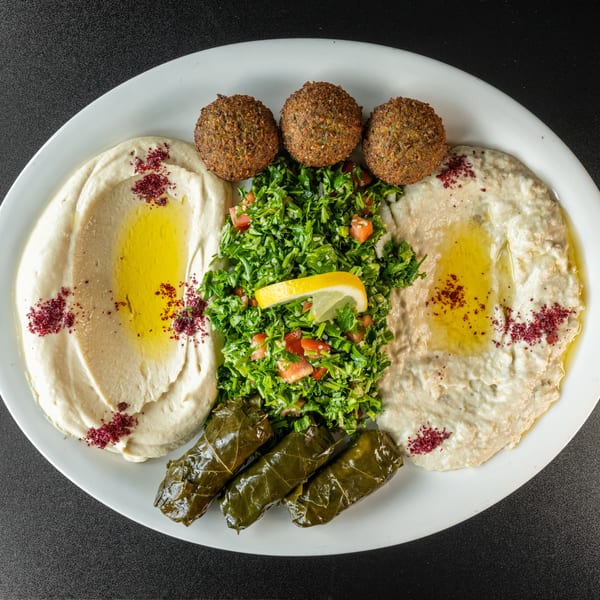 A platter with hummus, baba ghanoush, falafel, tabbouleh, and stuffed grape leaves.