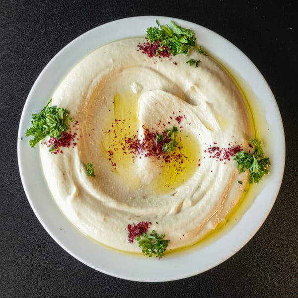 Creamy hummus drizzled with olive oil, sprinkled with sumac, and garnished with fresh parsley.
