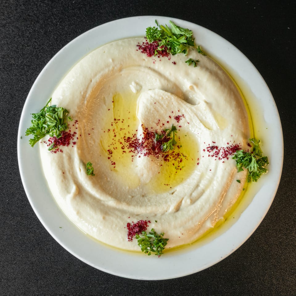 Creamy hummus drizzled with olive oil, sprinkled with sumac, and garnished with fresh parsley.