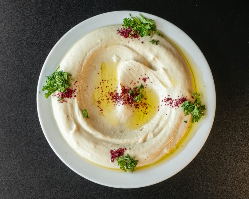 Creamy hummus drizzled with olive oil, sprinkled with sumac, and garnished with fresh parsley.